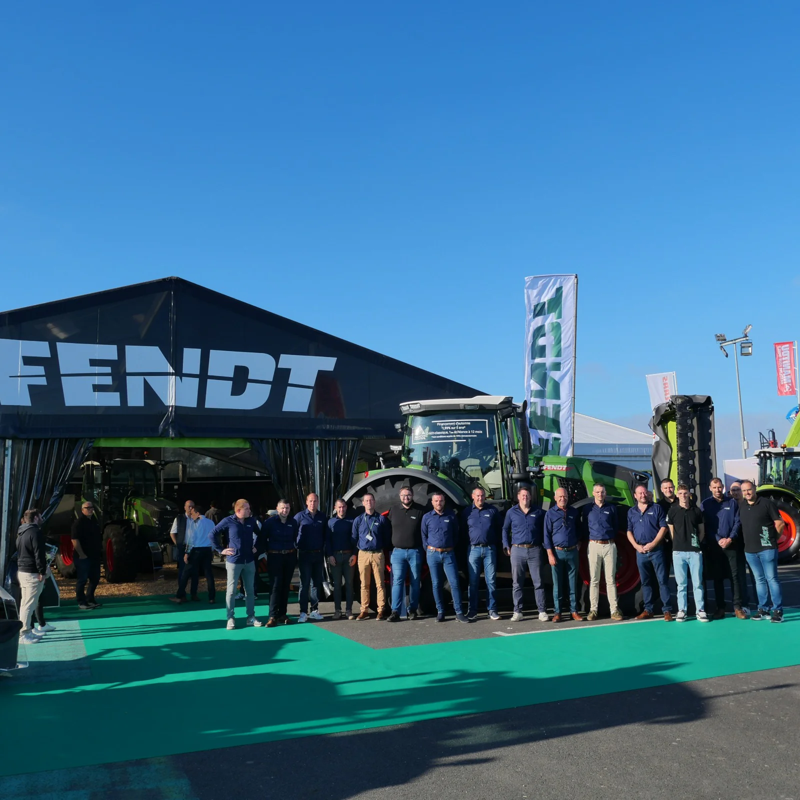 L'équipe commerciale d'Espace Agri pose en groupe devant le stand et les tracteurs Fendt au salon SPACE à Rennes sous un ciel bleu.